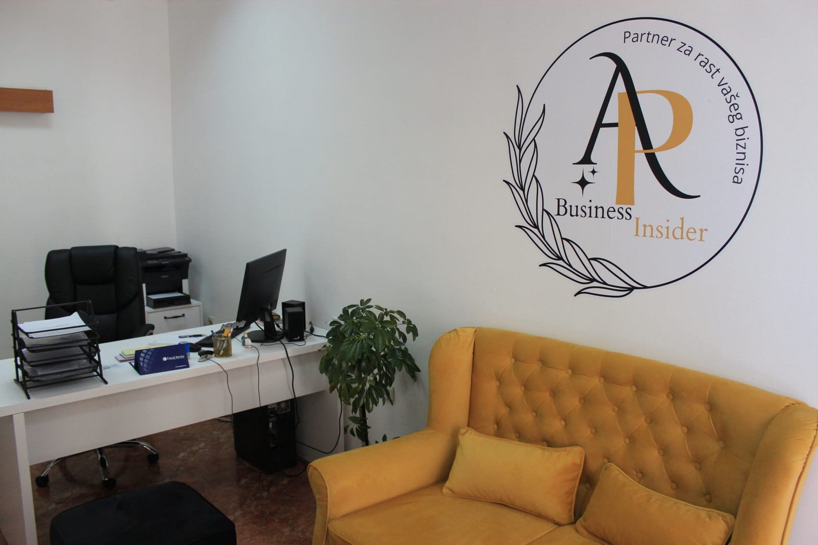 Büro von AP Business Insider: Schreibtisch, gelbes Sofa und Logo an der Wand